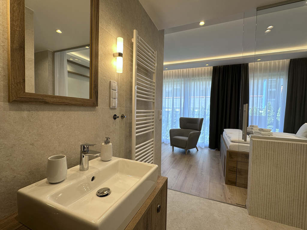 Badezimmer der Camilla Suite mit Waschbecken und Blick in den Schlafbereich mit Sessel
