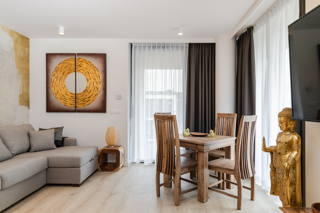 Wohnbereich der Queen Suite mit grauem Ecksofa, Holzesstisch und goldenem Rundbild