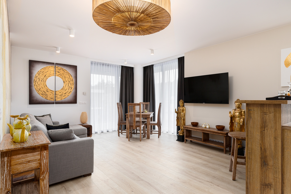 Offener Wohn- und Essbereich der Queen Suite mit Sofa, Wand-TV und Bambus-Deckenleuchte