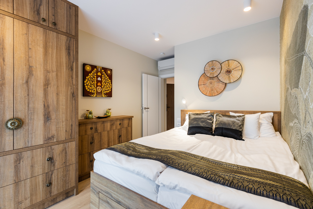 Doppelbett der Queen Suite mit Holzkleiderschrank, Kommode und thailändischem Wandbild