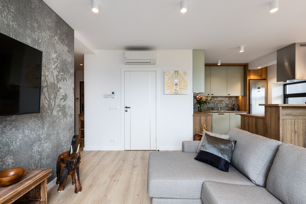 Wohnbereich der King Suite mit grauem Ecksofa, Wand-TV und offener Küche