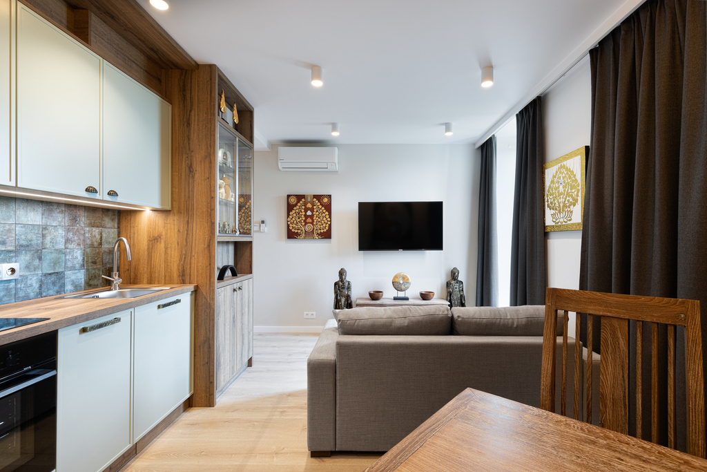 Offener Wohn- und Küchenbereich der Elephant Suite mit Ecksofa, Wand-TV und thailändischer Wandkunst